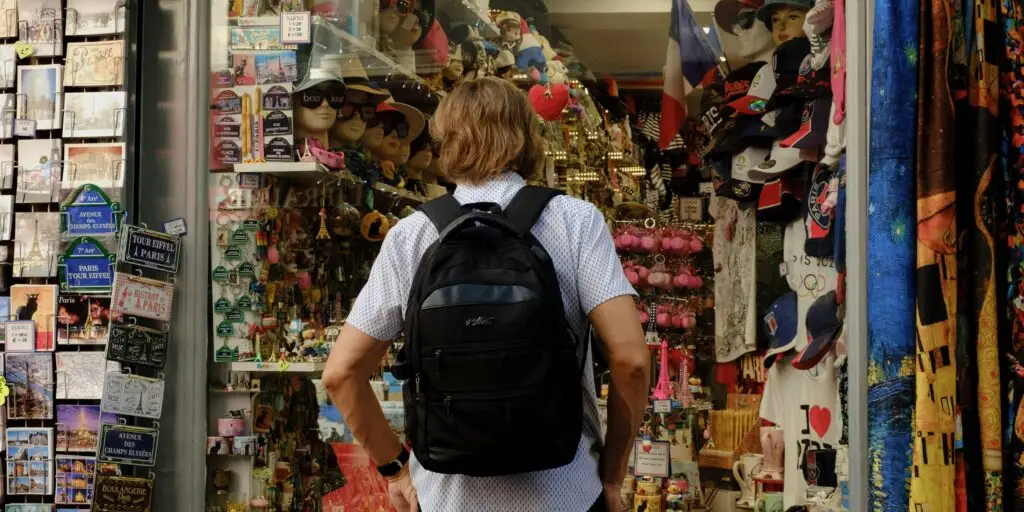 Local business in Yucatan, A man with a backpack stands outside a Paris-themed souvenir shop, exploring the vibrant items on display.