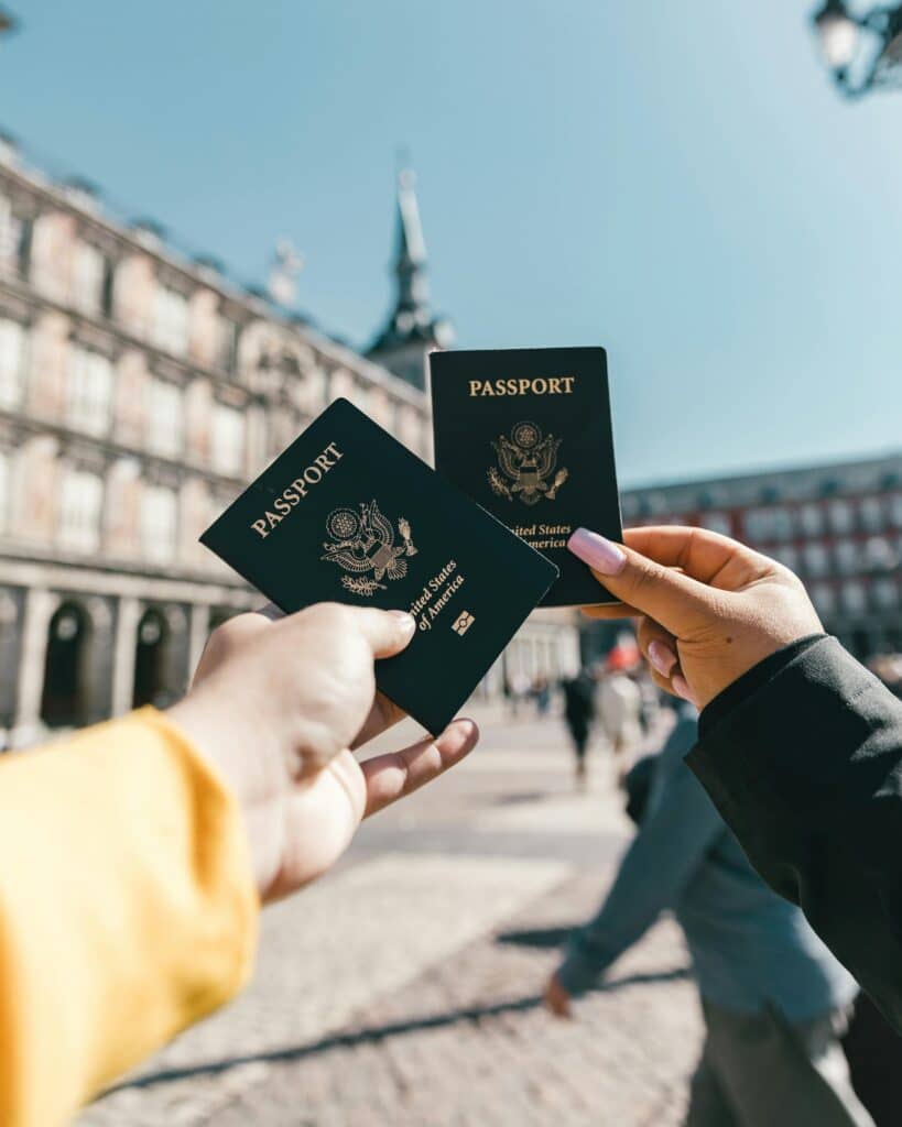 Travelers holding US passports at Plaza Mayor, Madrid, highlighting tourism and exploration.