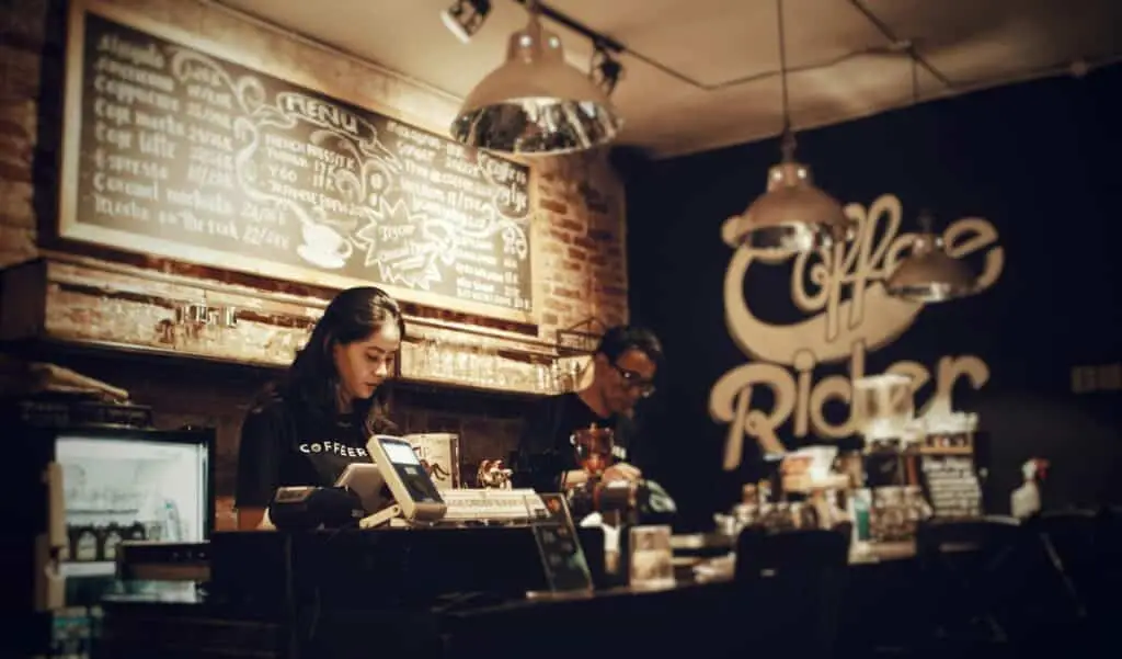 Local Yucatan business, Baristas preparing coffee. Cozy indoor setting with menu board.